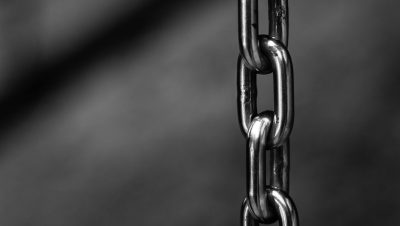 Detailed close-up of a strong shiny metallic chain link against a blurred background, emphasizing security.