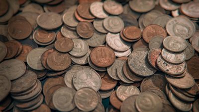A scattered collection of various vintage coins with copper and silver tones, depicting wealth and currency.
