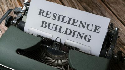 A vintage typewriter with the words 'RESILIENCE BUILDING' on a paper sheet.