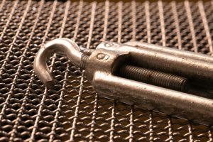 Detailed shot of a metal hook on a grid mesh, showcasing texture and industrial design.