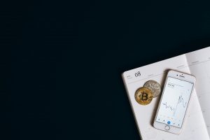 Smartphone displaying cryptocurrency data next to Bitcoin on a calendar offers finance and technology insights.